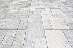 Close-up of a concrete driveway paved with various interlocking paving stones in gray and beige tones