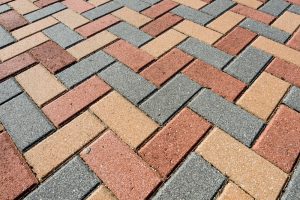 Red and gray rectangular bricks laid in a herringbone pattern for a sidewalk paving