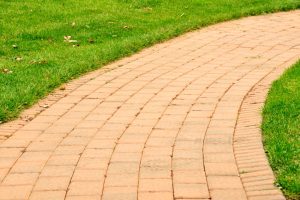 Curved brick walkway made from permeable paving stones surrounded by green lawn