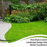 Lush greenery, stone wall, and curved walkway illustrate year-round beauty through custom landscape design