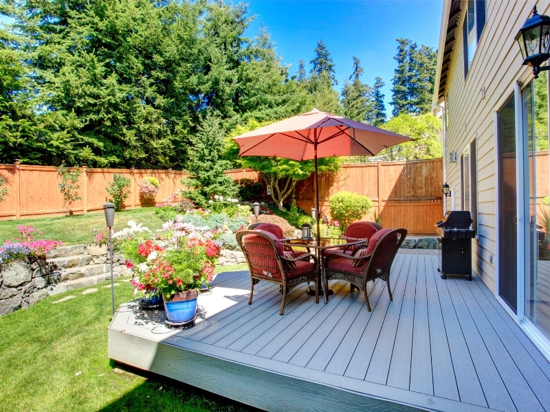 Patio paving with raised deck, outdoor seating, and flower arrangements.