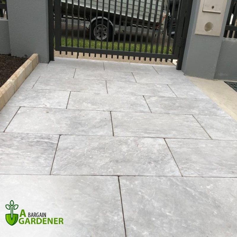 A driveway featuring a stone walkway and a decorative gate, showcasing elegant paving in Glenmore Park.