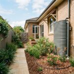 Low-water Sydney garden featuring drip irrigation, native shrubs, and a rainwater tank.