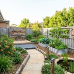 Modern sustainable Sydney backyard featuring native drought-tolerant plants, recycled stone pathways, edible gardens, solar lighting and wildlife-friendly landscaping.